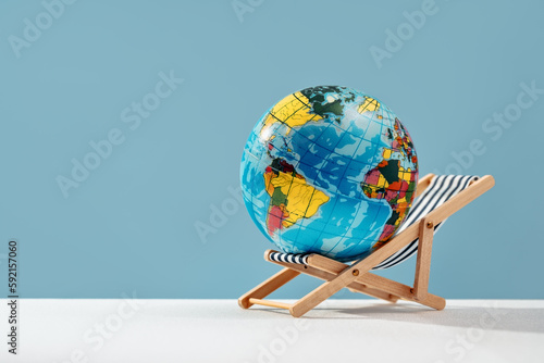 world globe resting on sun bed chair. Earth day. Global health care taking break or retirement and travel concept. Save the planet. Working or studying remotely concept. Vacation destination