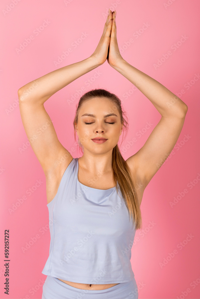 Young healthy Girl in gray sportswear is doing stretches and warm-up exercises. Isolated on pink background.