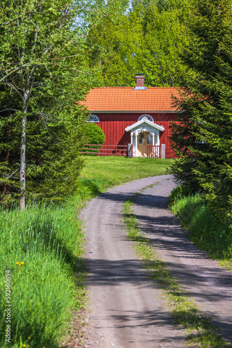 Red cottage by a gravel road in a forest