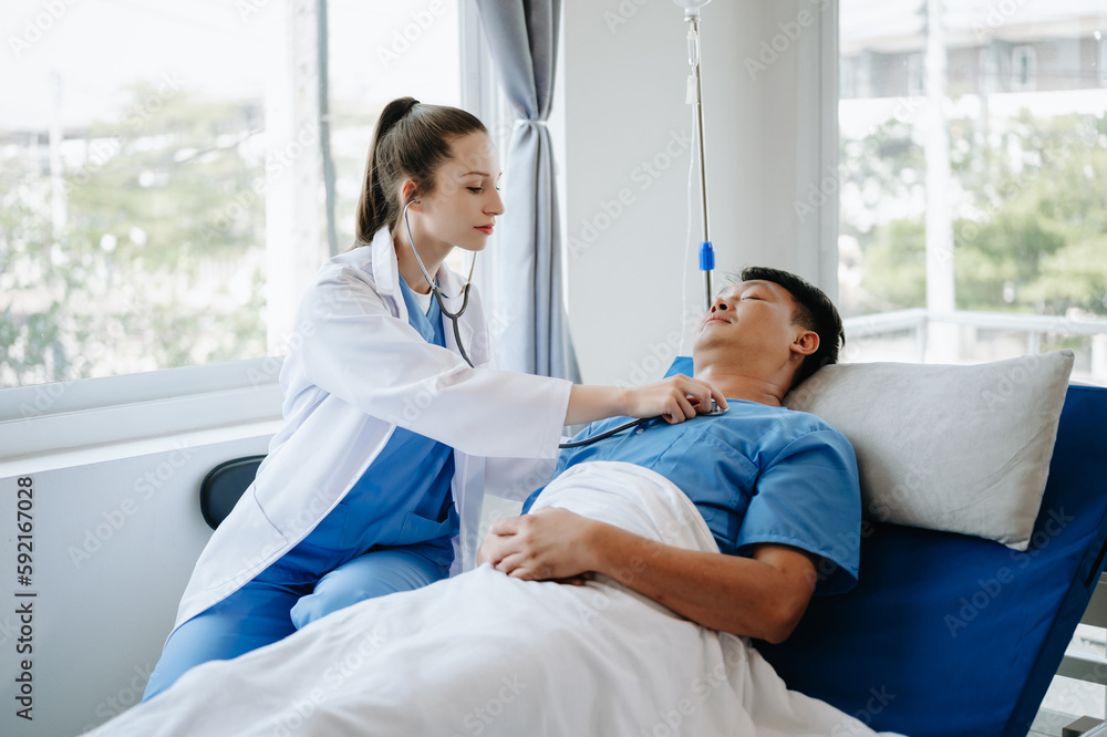 Doctor in white suit take notes while discussing and Asian elderly, man patient who lying on bed with receiving saline solution in hospital or clinic.. Doctor in white suit take notes while discussing and Asian elderly, man patient who lying on bed with receiving saline solution in hospital or clinic..