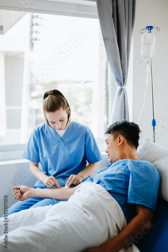  Friendly Female Head Nurse Making Rounds does Checkup on Patient Resting in Bed. She Checks tablet while Man Fully Recovering after Successful Surgery in hospital..