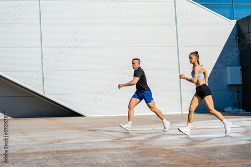 Male and female fitness instructors jogging outdoors