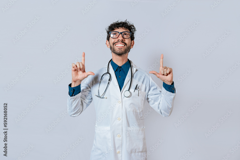 Handsome doctor pointing up. Smiling doctor pointing a promo up. Male doctor looking and pointing up isolated Handsome doctor pointing up. Smiling doctor pointing a promo up. Male doctor looking and pointing up isolated