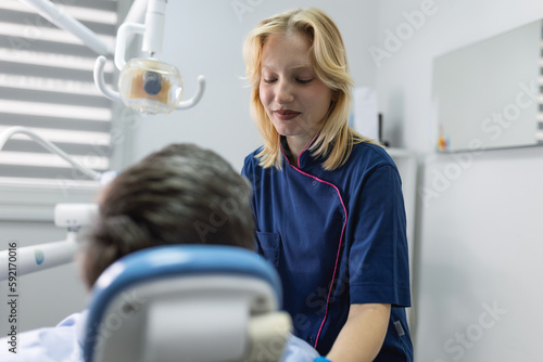 Female dentist in dental office talking with patient and preparing for treatment.