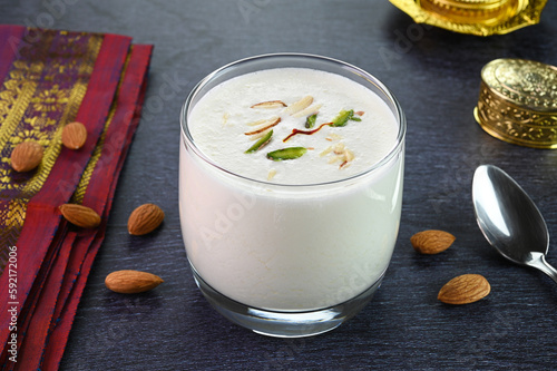 Sweet lassi served in a glass cup garnished with saffron, almonds and pistachios.