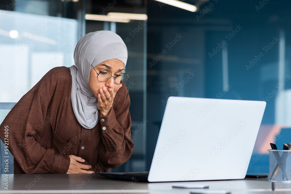 Sick business woman in hijab working inside office at workplace, nausea