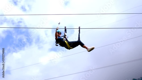 Slomo of young man riding zip line at Baños in Ecuador, tracking pan
