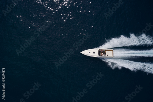 Large speed boat moving at high speed. Top view of a white boat sailing to the blue sea. Travel - image.Drone view of a boat sailing. Motor boat in the sea.