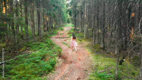 Girl walking on path in the woods view from drone