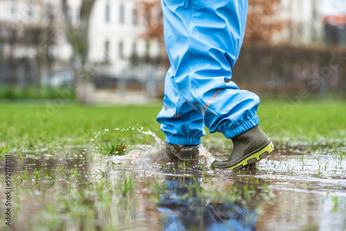 Cutout of a young child in park having fun in a puddle during rainy weather