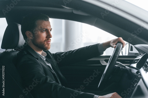 Serious facial expression. Driving the car. Man in formal business clothes is sitting in the modern automobile © standret