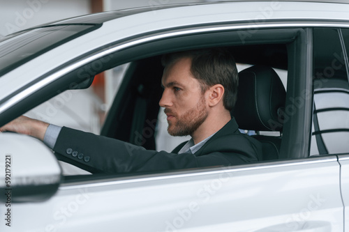 Serious facial expression. Driving the car. Man in formal business clothes is sitting in the modern automobile