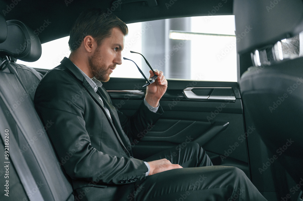 In comfortable modern automobile. Man in formal business clothes