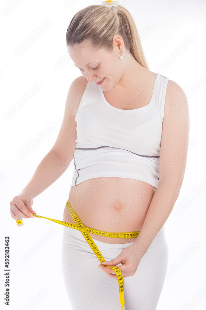 One Positive Pregnant Caucasian Woman Posing With Yellow Measurement Tape In White Shirt And Pants One Positive Pregnant Caucasian Woman Posing With Yellow Measurement Tape In White Shirt And Pants