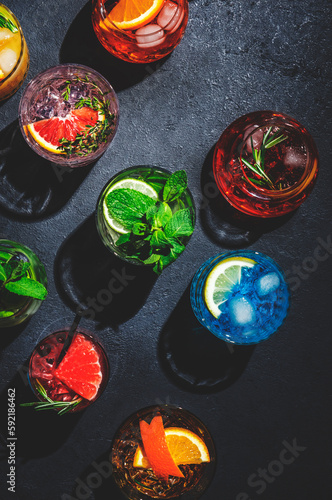 Cocktails set on black bar counter, top view. Mixology concept. Assortment of colorful strong and low alcohol drinks for cocktail party. Dark background, hard light