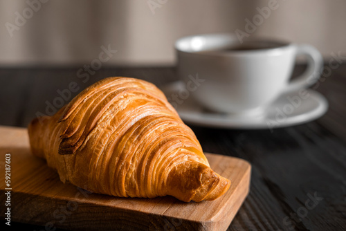 Coffee cup with croissant on a rustic dark wooden table. Food series. Two tasty fresh croissants  jam  orange juice. Continental breakfast served with freshly baked pastry. Close up view  Good morning