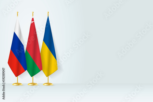 Flags of Russia, Belarus and Ukraine stand in row on indoor flagpole.