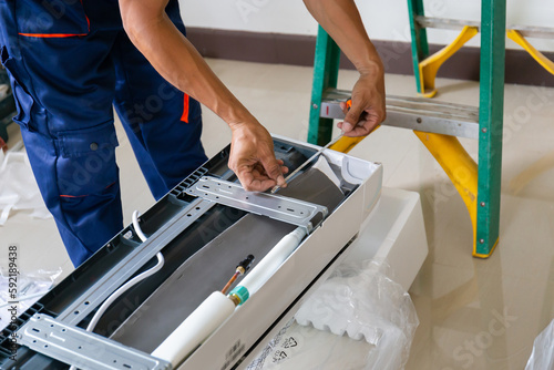 Technician man installing an air conditioning in a client house, Young repairman fixing air conditioner unit, Maintenance and repairing concepts