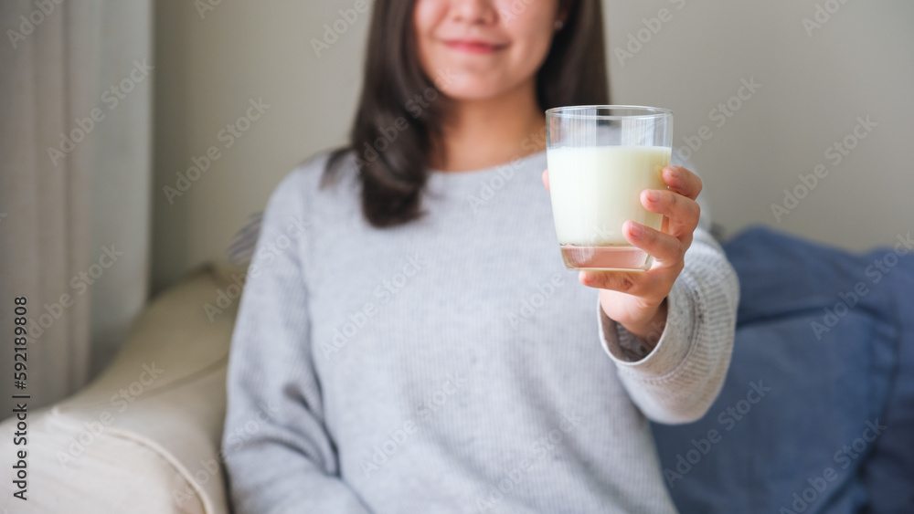 Closeup image of a young woman holding and showing a glass of fresh milk Closeup image of a young woman holding and showing a glass of fresh milk