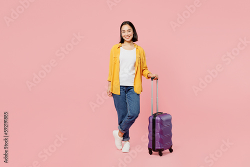 Full body traveler smiling woman wear casual clothes hold suitcase bag isolated on plain pastel pink background. Tourist travel abroad in free spare time rest getaway Air flight trip journey concept. #592191885