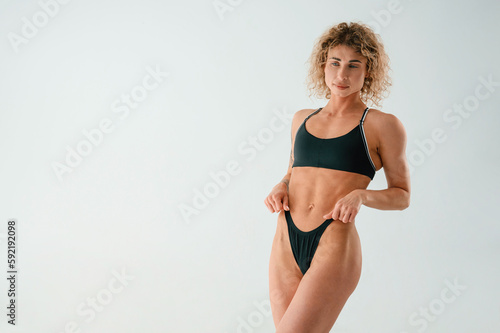 Beautiful abs. Young caucasian woman with athletic body shape is indoors at daytime