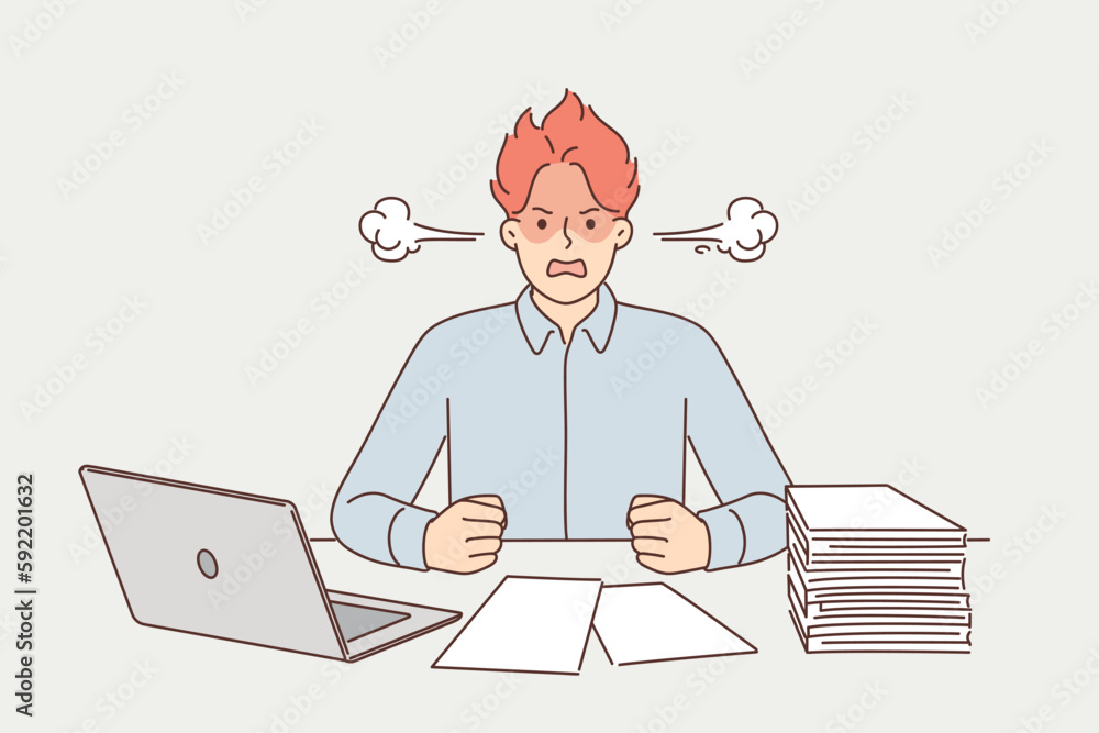 Angry man suffering from overwork and paperwork sitting at office desk with laptop Angry man suffering from overwork and paperwork sitting at office desk with laptop