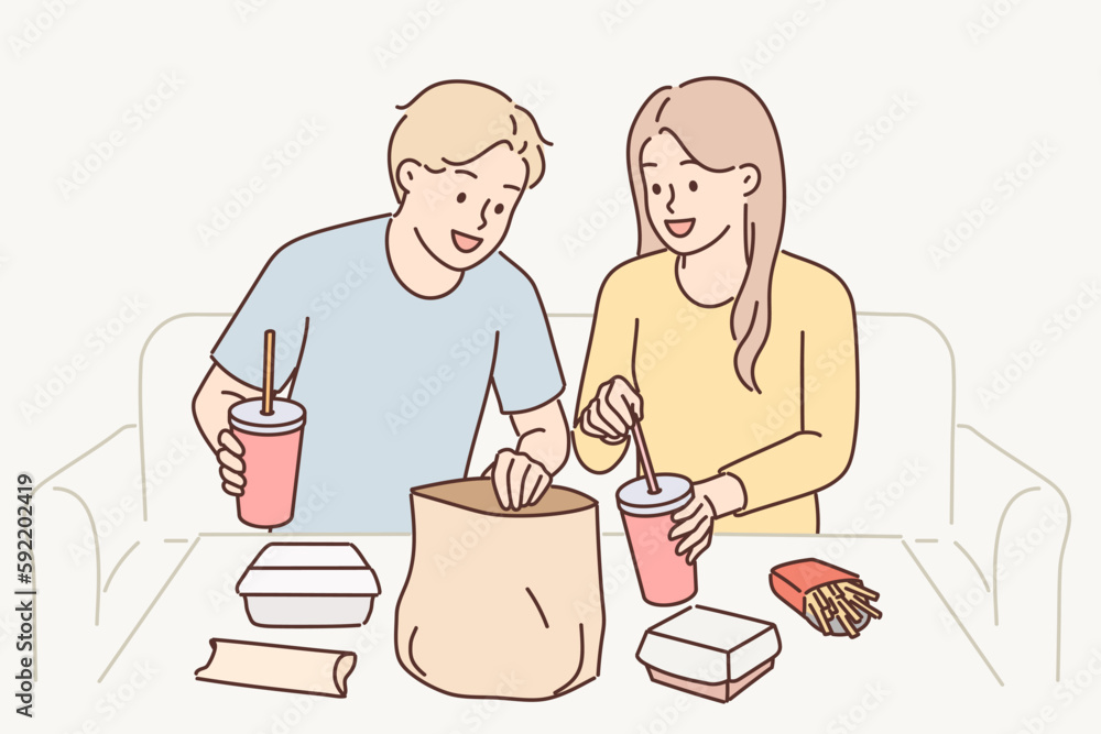 Man and woman have lunch sitting at table enjoy takeout food delivered by courier from restaurant Man and woman have lunch sitting at table enjoy takeout food delivered by courier from restaurant