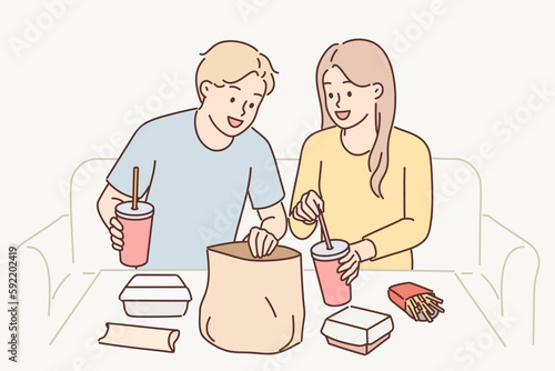 Man and woman have lunch sitting at table enjoy takeout food delivered by courier from restaurant