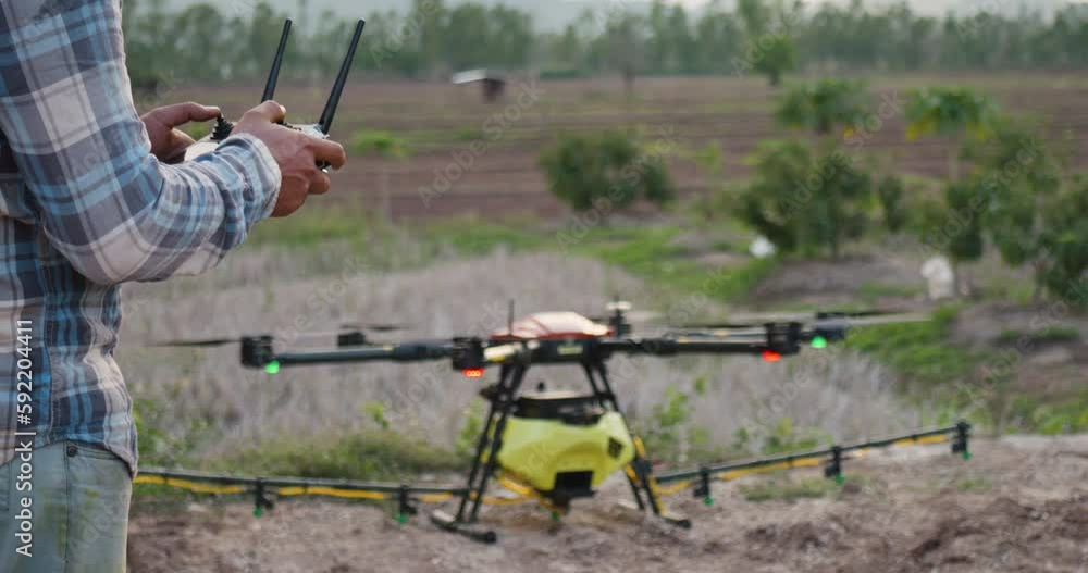 Farmer start using drone controller or drone transmitter a remote control for agriculture sprayer drone in rural area countryside farm Farmer start using drone controller or drone transmitter a remote control for agriculture sprayer drone in rural area countryside farm