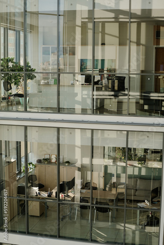 Vertical image of modern office building with glass walls and workplaces for business people inside of it
