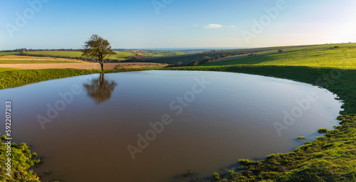 Evening golden hour at Ditchling Beacon dew pond on the south downs way East Sussex south east England