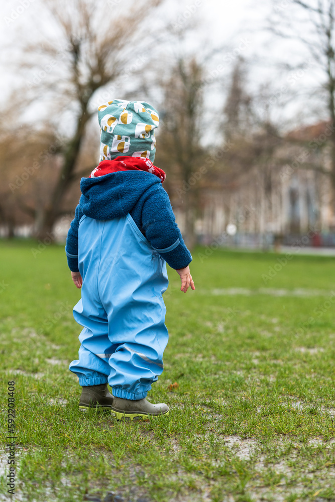 Fototapeta premium A young child in a park at rainy weather