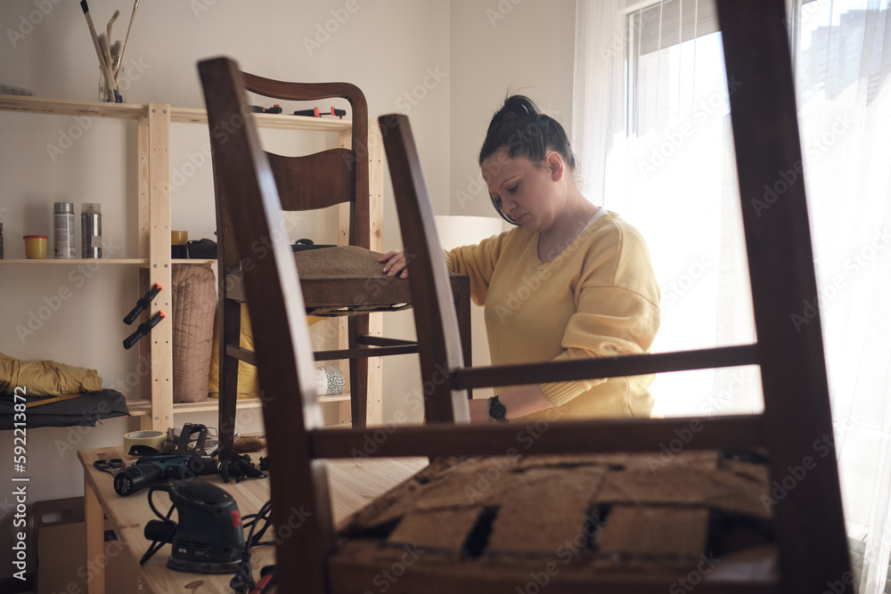 Woman working in a small home workshop for furniture repairing and restoration.