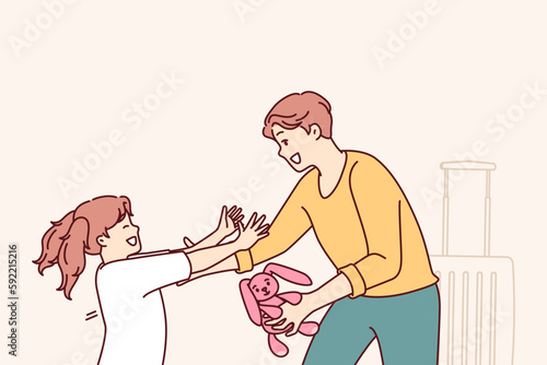 Little girl runs to father who returned from long business trip with gift and wants to hug daughter. Man with toy hare in hand stands near suitcase and rejoices when he sees daughter running towards