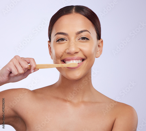 Portrait  dental or happy girl brushing teeth with smile for healthy oral hygiene in studio white background. Beauty or Brazilian woman model cleaning mouth with a natural bamboo wooden toothbrush