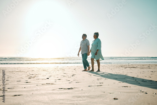 Sunset, mockup and an old couple walking on the beach, holding hands during a romantic date together. Love, nature or bonding with a senior man and woman taking a walk on the coast during summer