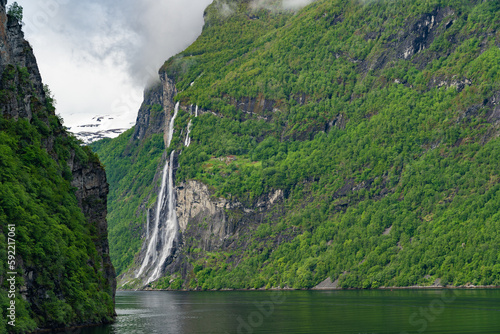 Beautiful landscape with snowy mountain peaks and waterfalls in Geiranger fjord, Norway