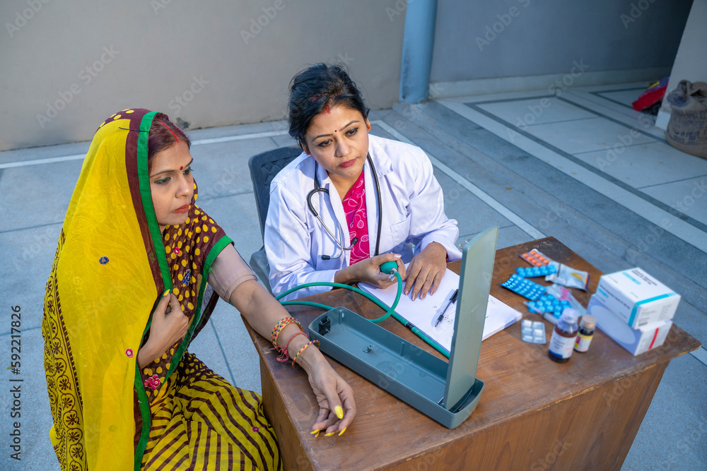 Indian female doctor checking blood pressure of rural woman at clinic