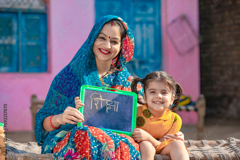 Indian rural woman with her little daughter showing chalk slate