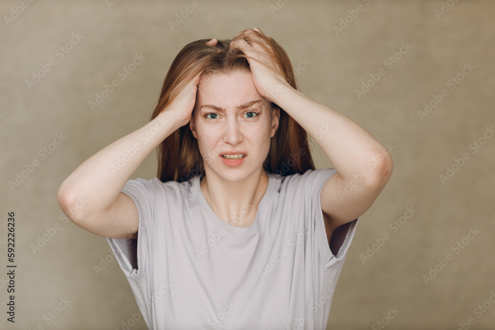 Portrait of young sad upset caucasian woman looking at camera against beige background Portrait of young sad upset caucasian woman looking at camera against beige background