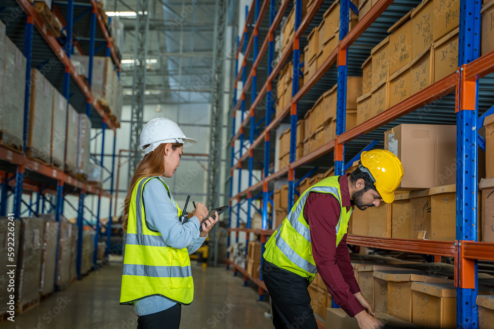 Warehouse worker uses digital tablet for checking stock in a large distribution warehouse. Warehouse worker uses digital tablet for checking stock in a large distribution warehouse.