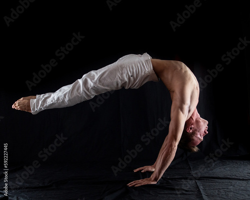 flexible circus artist keep balance on hands on a black background. concept of contortion and flexibility 