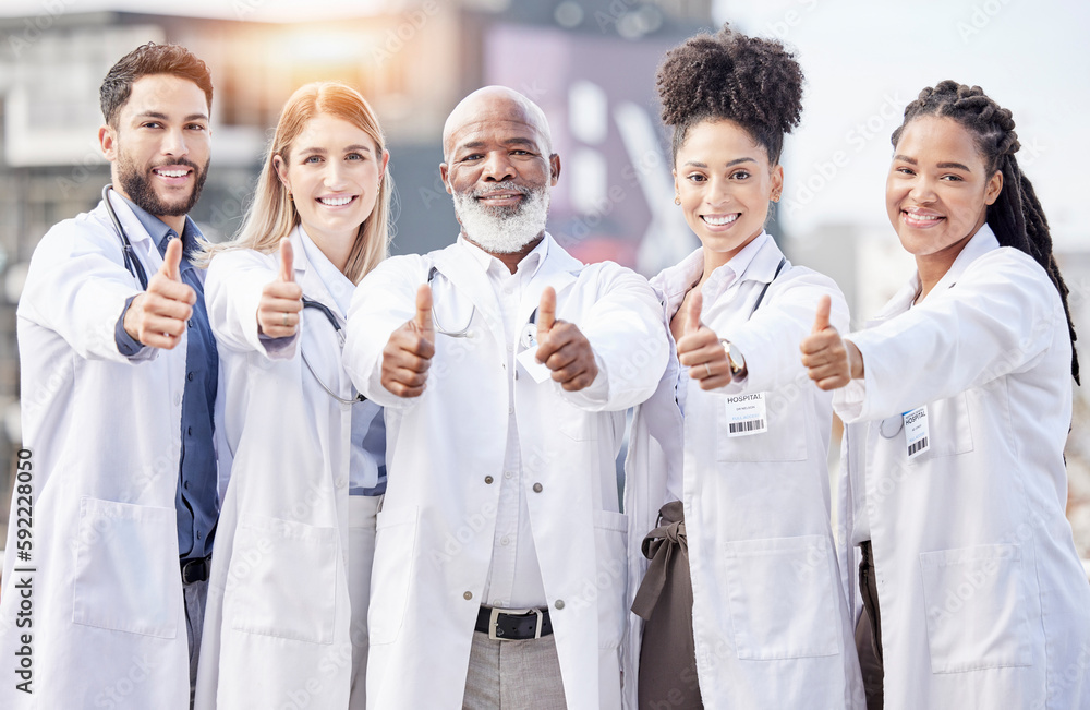 Portrait, collaboration and thumbs up with a team of doctors standing outside of a hospital together. Teamwork, thank you or motivation with a team of professional healthcare workers feeling positive Portrait, collaboration and thumbs up with a team of doctors standing outside of a hospital together. Teamwork, thank you or motivation with a team of professional healthcare workers feeling positive