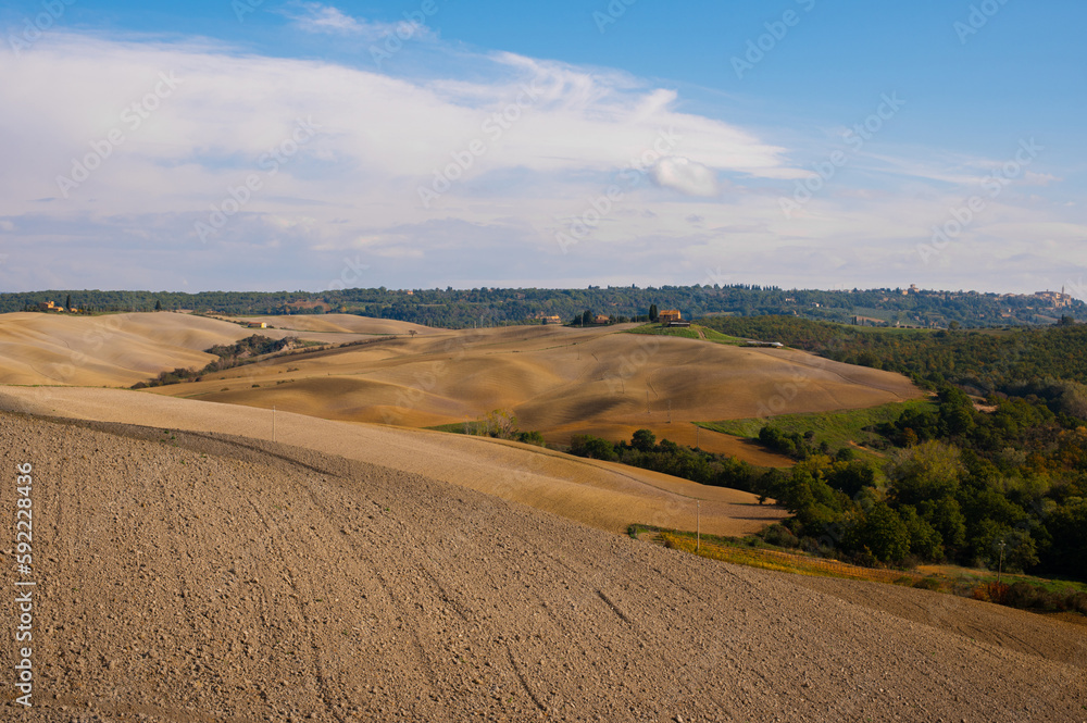 The picturesque authentic Italian scenery with plowed fields and blue sky in Tuscany, Italy. Pastoral landscape of Tuscany.