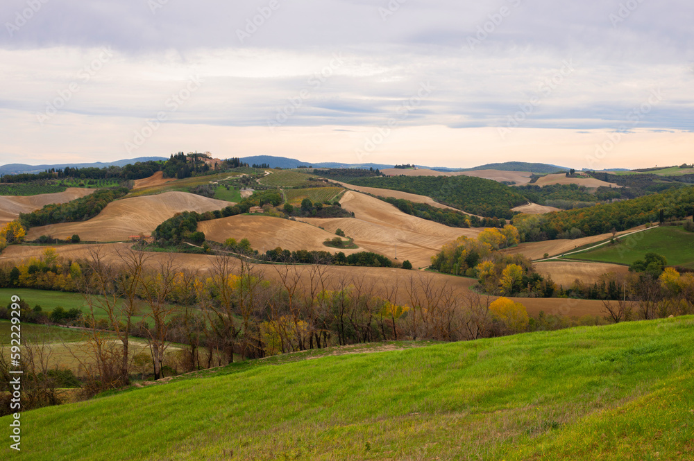 Beautiful Italian Landscape in Tuscany with famous cypress trees and cloudy sky. Pastoral landscape of Tuscany with plowed fields.