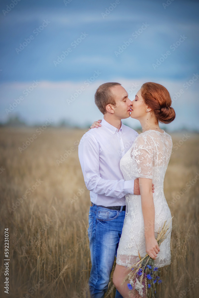 Love story. Wedding day. Newlyweds. Boho style wedding. Bride and groom.A beautiful girl and a guy in a wheat field. Bride with a bouquet of wild flowers.Tenderness.Love.Summer day. Happiness.Portrait