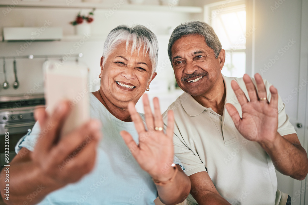 Obraz premium Video call, waving and elderly couple on phone, happy and smile in their home kitchen. Smartphone, love and old people greeting, excited and cheerful for online conversation and enjoying retirement