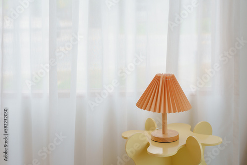 Wooden lamp on cute yellow table with white curtain background with copy space.