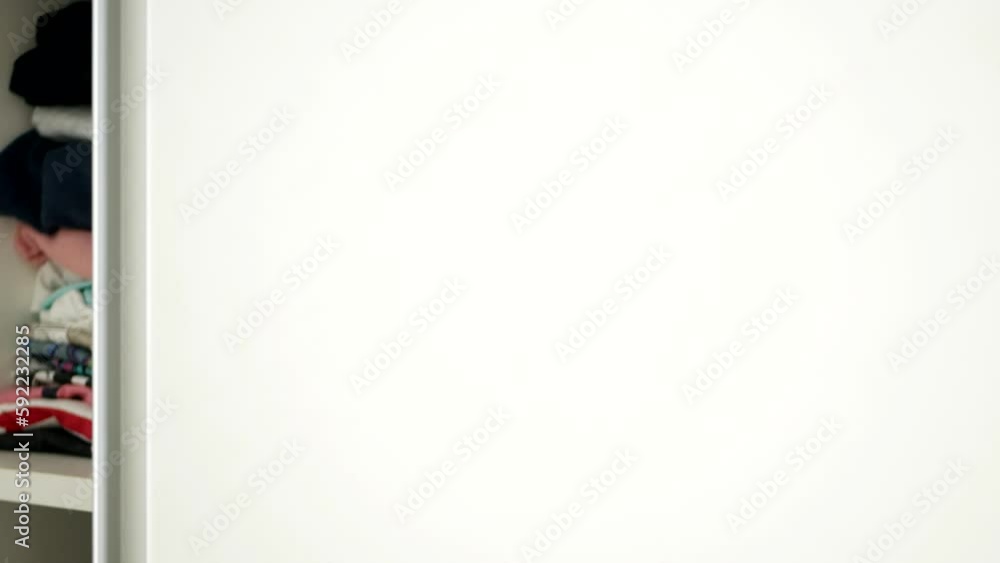 One Person Closing the Door of a Closet with Clean Clothes Folded on the Shelves. One Person Closing the Door of a Closet with Clean Clothes Folded on the Shelves.