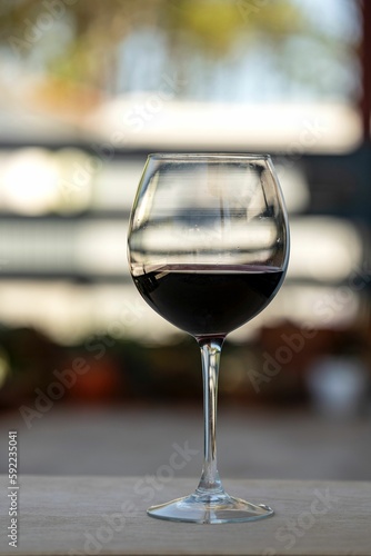 Vertical shot of a glass with red wine on a balcony table